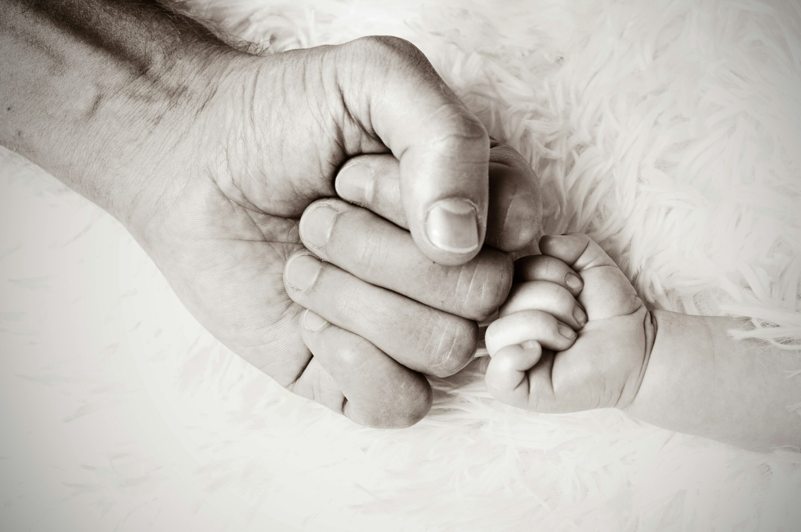 a close up of a person holding a baby's hand